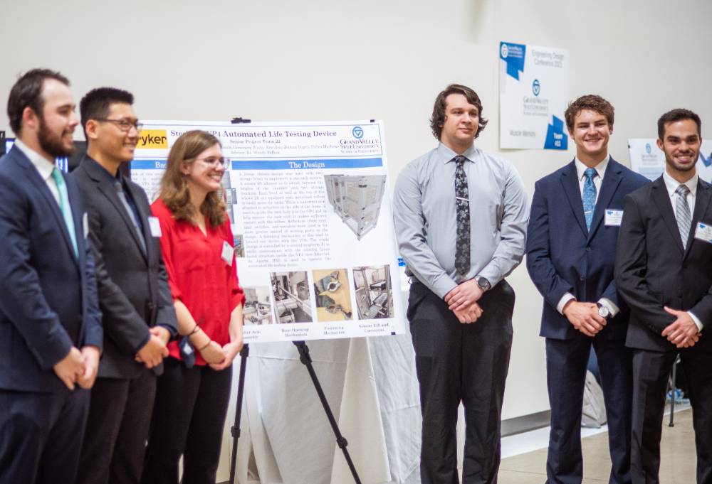 A student team stands by their poster presentation